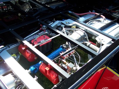 1972 Ford Ranchero - The undercarriage of a vehicle is visible, with various mechanical components and a red battery.