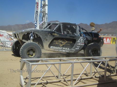 1990 Ford Bronco - black off-road race buggy numbered 106, spattered with mud and wearing BFGoodrich and PIAA decals, crosses a desert course.