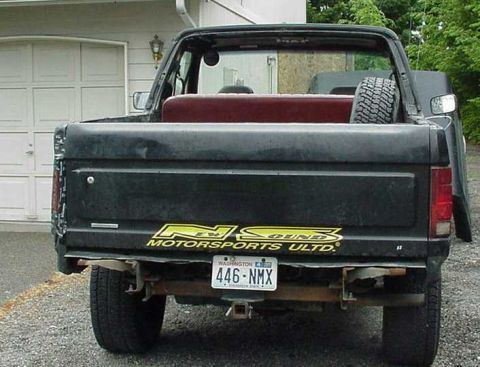 1985 Ford Bronco - Rear view of a black 1985 Ford Bronco pickup truck with a spare tire in the bed.