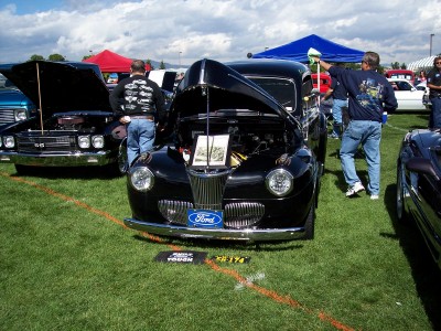 1972 Ford Ranchero - A black 1940 Ford Coupe is displayed with its hood open at an outdoor car show.