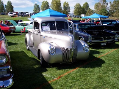 1972 Ford Ranchero - A classic Ford pickup truck is displayed at an outdoor event with other vehicles and tents visible.