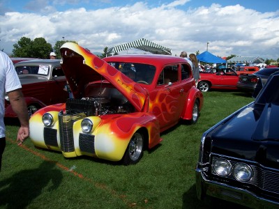 1972 Ford Ranchero - A custom hot rod with flame paintwork is displayed at an outdoor car show.