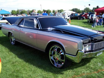 1972 Ford Ranchero - A two-tone 1967 Lincoln Continental coupe with custom wheels is displayed on a grassy field at an outdoor car show.