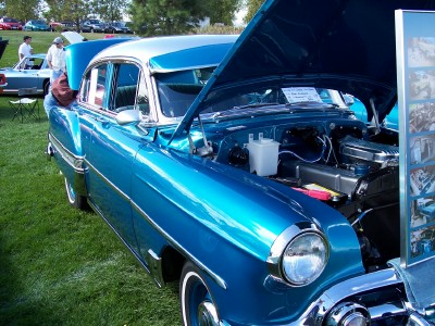 1972 Ford Ranchero - A blue sedan is displayed with its hood open at an outdoor event.
