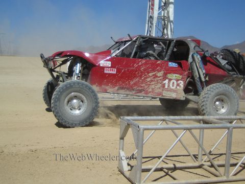 1990 Ford Bronco - red off-road race buggy numbered 103 with SCORE decals races over a dusty desert course.