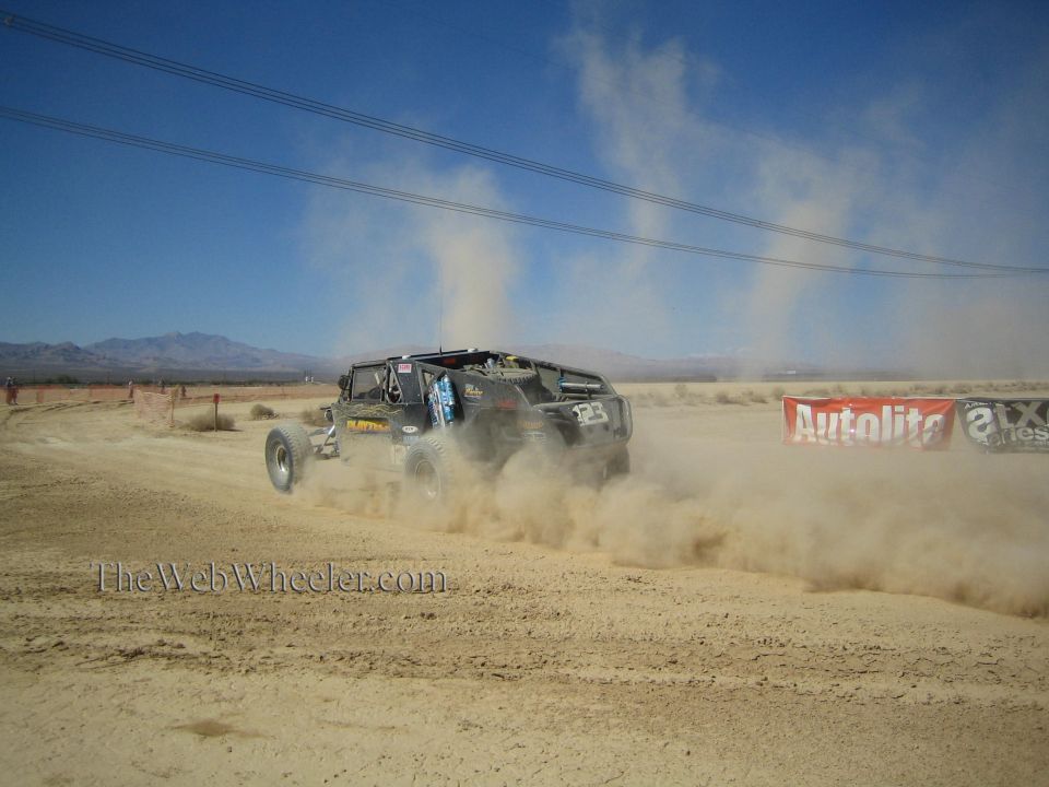 Off-road race buggy speeding away on a dusty desert course