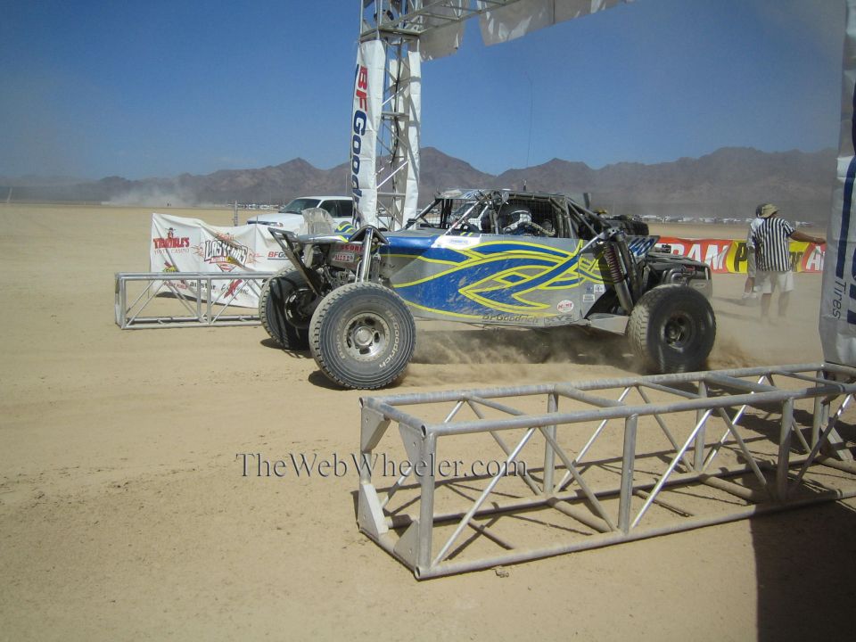 Blue and yellow off-road race buggy at desert start under BFGoodrich arch