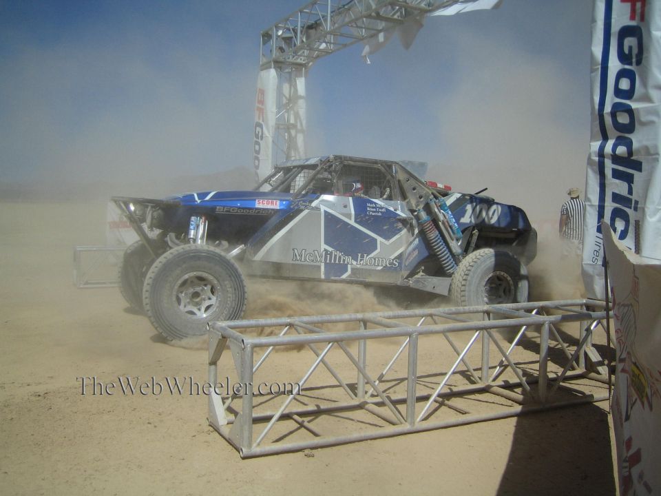 Blue off-road race buggy #200 with McMillin Homes livery throwing up dust