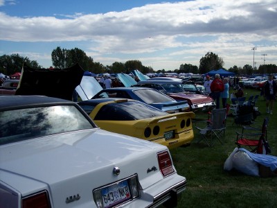 1972 Ford Ranchero - Multiple vehicles are parked on grass under a cloudy sky at an outdoor event.