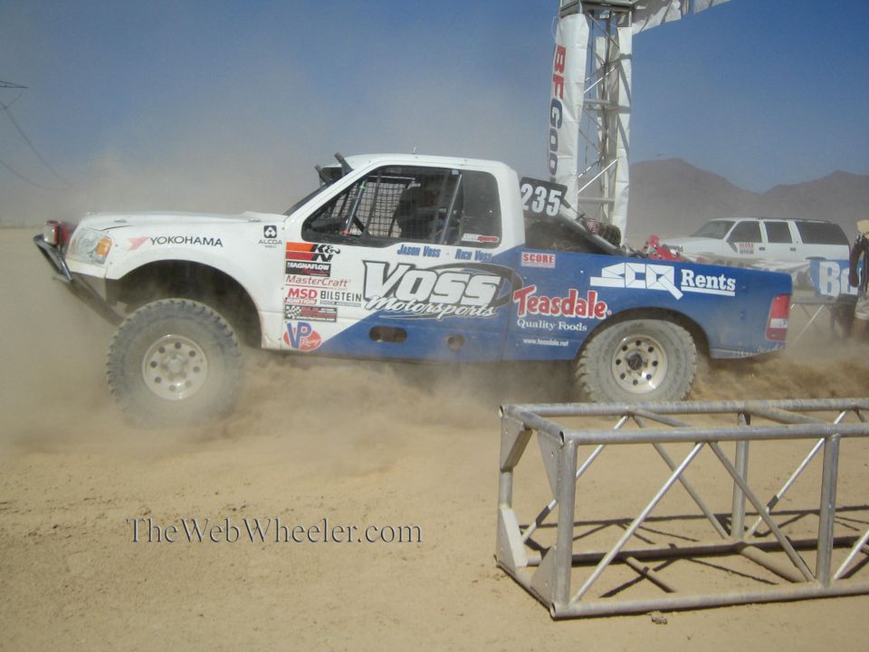 White and blue off-road race truck #235 with Voss Motorsports livery on desert course