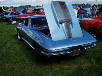 1972 Ford Ranchero - A light blue 1965 Chevrolet Corvette Sting Ray is displayed with its hood open at an outdoor car show.