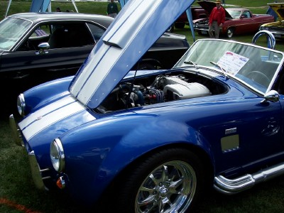 1972 Ford Ranchero - A blue convertible with racing stripes is displayed with its hood open, revealing the engine.