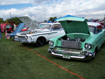 1972 Ford Ranchero - Two classic cars, a 1957 Chevy and a white 1960s model, are displayed with hoods open at an outdoor car show.