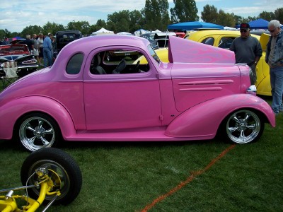 1972 Ford Ranchero - A pink hot rod coupe with custom modifications is displayed at an outdoor car show.