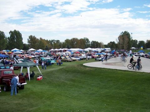 1972 Ford Ranchero - A wide view of an outdoor car show event with numerous vehicles displayed under tents and on a grassy field, alongside a skate park.