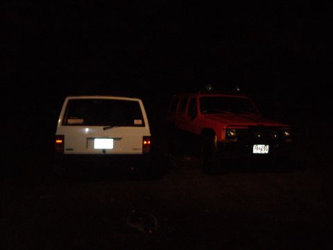 1990 Jeep Cherokee - Two Jeep Cherokees parked at night, one white and one red.