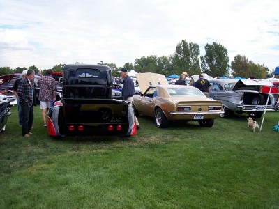 1972 Ford Ranchero - Several vehicles are on display at an outdoor event, with people milling around and looking at the cars.