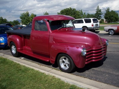 1972 Ford Ranchero - A custom maroon pickup truck with flame decals and chrome wheels is parked on the side of the road.