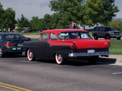 1972 Ford Ranchero - A two-tone red and black 1956 Ford Fairlane Crown Victoria is seen from the rear, driving on a sunny day.