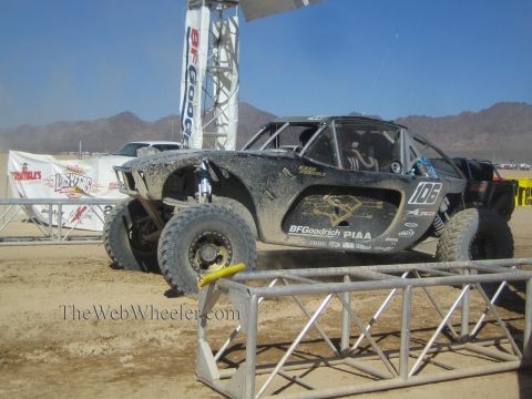 1990 Ford Bronco - black number 108 off-road race truck with BFGoodrich and PIAA decals sits on a dirt course near a race gantry.