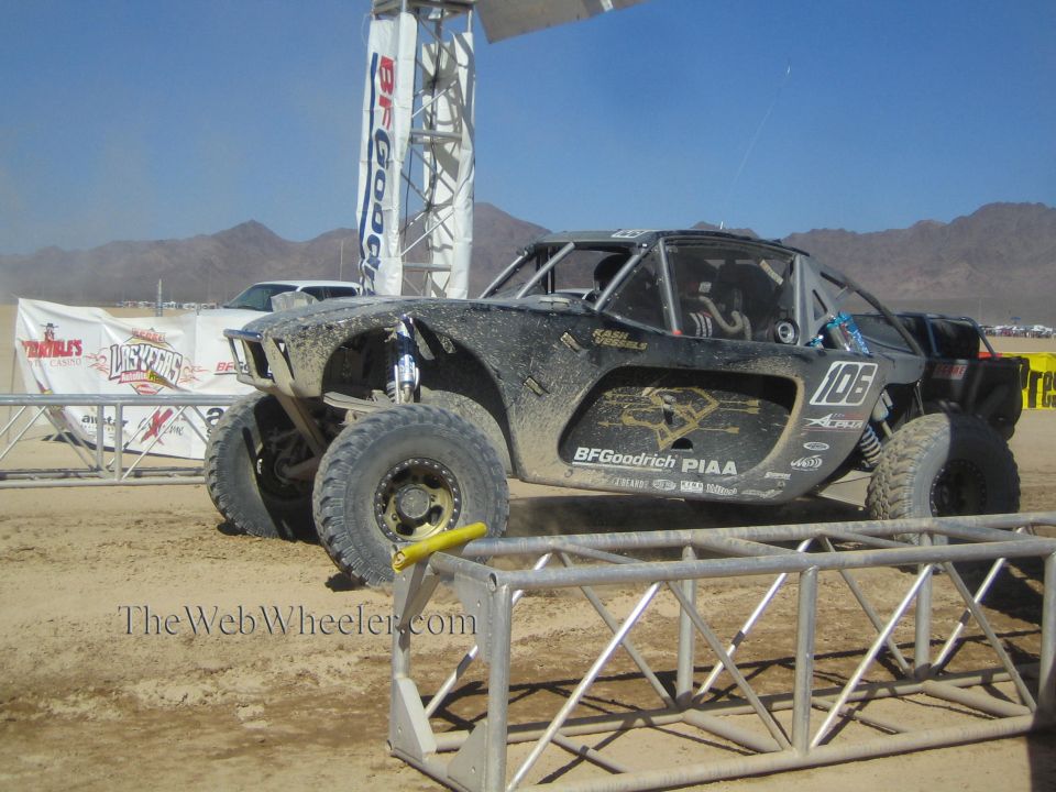 Black No. 108 off-road race truck on dirt course beside BFGoodrich gantry