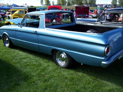 1972 Ford Ranchero - A blue pickup truck with a bed is parked on the grass at an outdoor car show with other vehicles present.