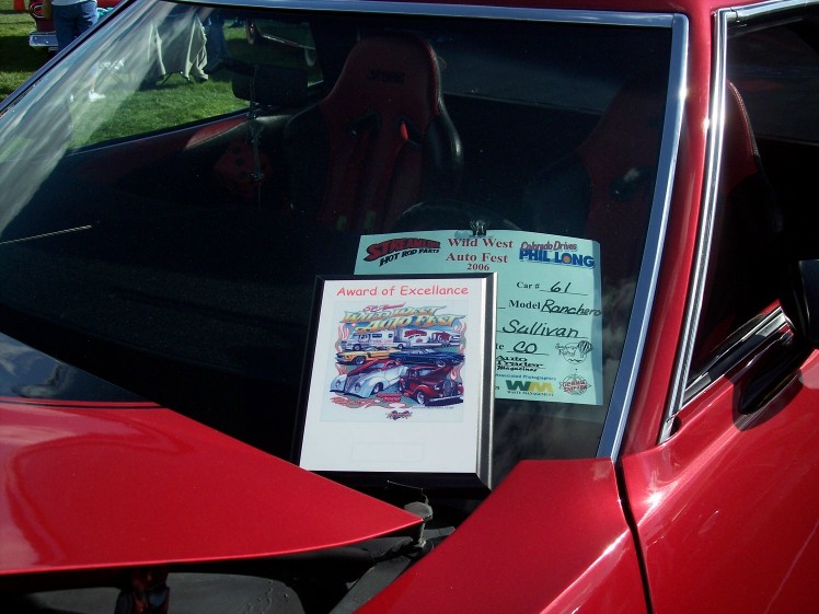 Red car interior with racing seats and a windshield full of awards from a car show