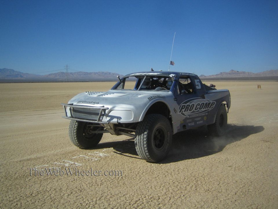 Silver Pro Comp No. 5 off-road race truck on flat desert course