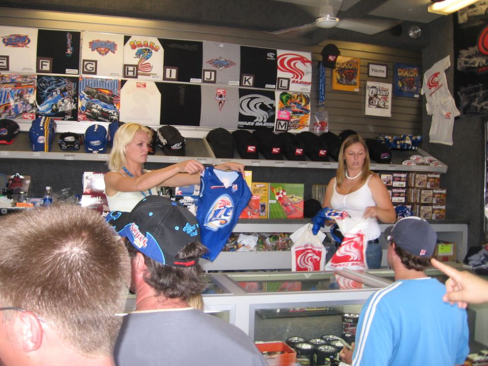 People in a store looking at NASCAR merchandise, including shirts and hats