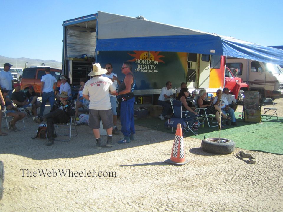 People gathered under a Horizon Realty Off Road Racing canopy at a desert pit