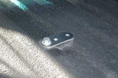 1986 Ford Bronco - Close-up of a metal bracket and bolt on a textured surface, possibly part of an auxiliary tank installation.