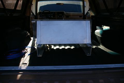 1986 Ford Bronco - An auxiliary fuel tank is installed in the cargo area of a vehicle, with the dashboard and steering wheel visible.