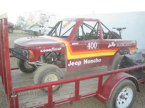 1990 Ford Bronco - maroon 'Jeep Honcho' number 400 off-road race truck with Goodyear and La Paz livery sits on a red utility trailer.
