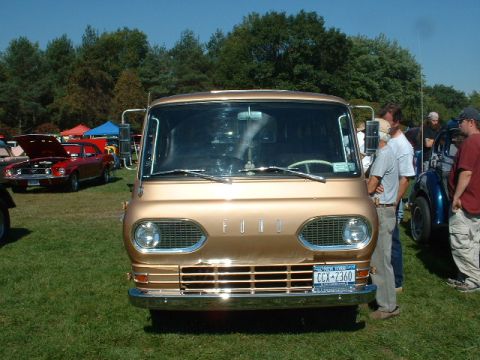 1978 Ford Mustang II - Gold 1961 Ford Econoline van parked on grass at an outdoor car show.