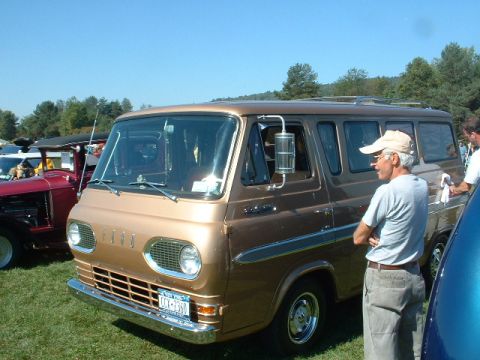 1978 Ford Mustang II - A man stands beside a vintage brown Ford Econoline van at an outdoor event.
