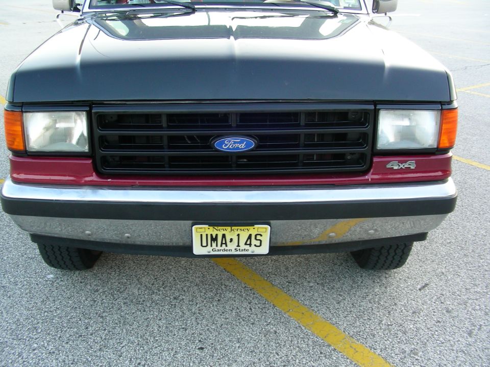 Front view of a 1990 Ford Bronco with a black grille and maroon lower panel