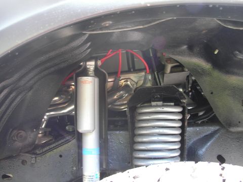 1994 Ford Bronco - Close-up view of the engine bay, showing a shock absorber, coil spring, and red spark plug wires.