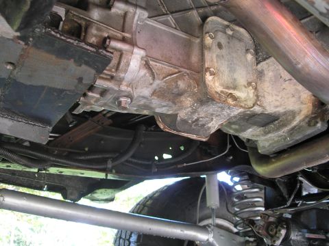 1994 Ford Bronco - The underside of a vehicle shows the transmission, exhaust system, and suspension parts.