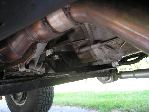 1994 Ford Bronco - Close-up view of the underside of a vehicle, focusing on the transmission and exhaust components.