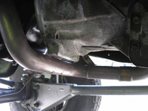 1994 Ford Bronco - The photo shows the undercarriage of a vehicle, focusing on the exhaust pipe and suspension parts.
