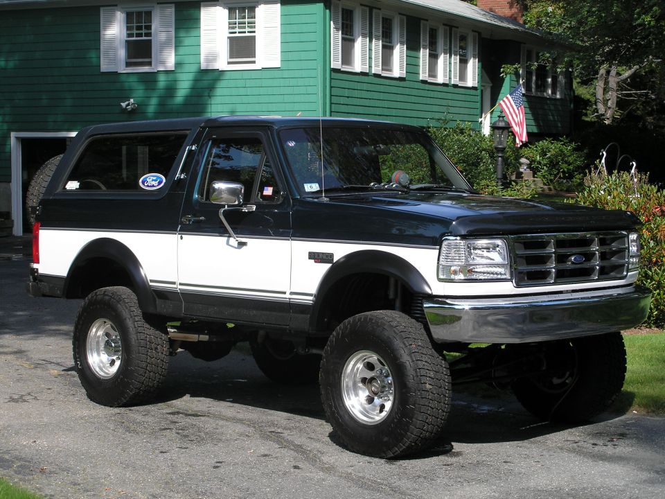 Black and white Ford Bronco with lifted suspension and off-road tires parked on asphalt