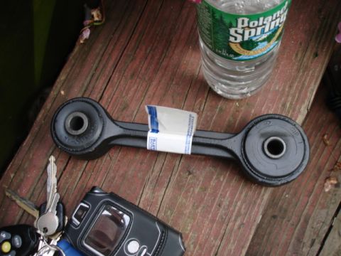 1997 Ford Crown Victoria - A car suspension part is shown on a wooden deck next to keys and a bottle of water.