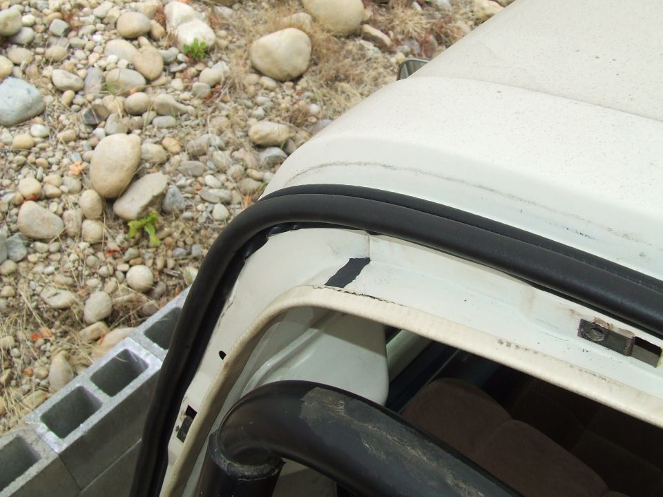 Close-up of black rubber seal along the front lip of a white removable hardtop