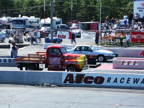 2001 Mercury Grand Marquis - A classic pickup truck and a sedan are lined up at a drag strip, with spectators in the background.