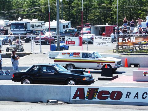 2001 Mercury Grand Marquis - Two cars are lined up on a drag strip, with spectators and RVs in the background.