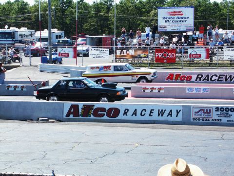 2001 Mercury Grand Marquis - Two cars are staged at the starting line of a drag race, with spectators in the background.