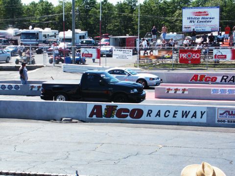 2001 Mercury Grand Marquis - Two vehicles are lined up at a drag strip, with spectators in the background.