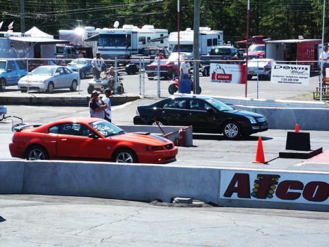 2001 Mercury Grand Marquis - Two cars, a red sports car and a black sedan, are positioned on a race track.