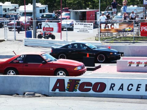 2001 Mercury Grand Marquis - Two cars are lined up at a drag strip, ready for a race.