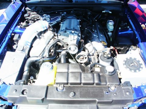 2001 Mercury Grand Marquis - The engine bay of a blue vehicle features a large supercharger and various engine parts.